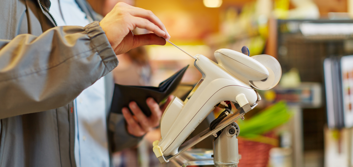 Mann zahlt am Kartenterminal im Supermarkt