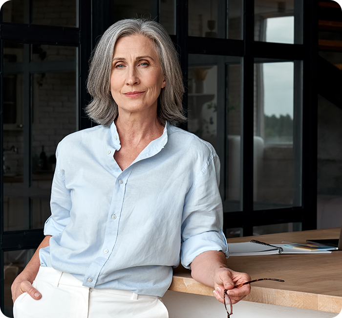 Dame mittleren Alters steht angelehnt am Tisch