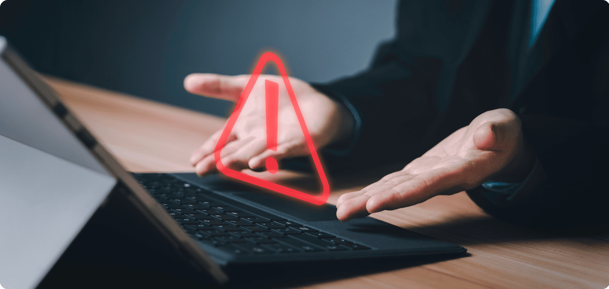 Hilflose Geste zweiter Hände vor Tastatur, über der ein rotes Warnzeichen schwebt