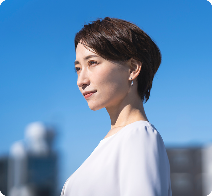 japanese woman looking to the left side, blue sky and buildings in background